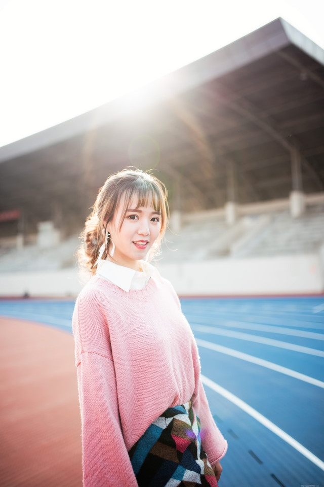 二月操场粉色毛衣美女抵御早春寒气阳光写真