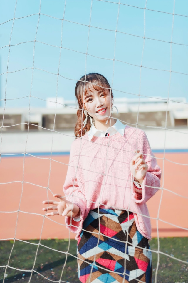 二月操场粉色毛衣美女抵御早春寒气阳光写真