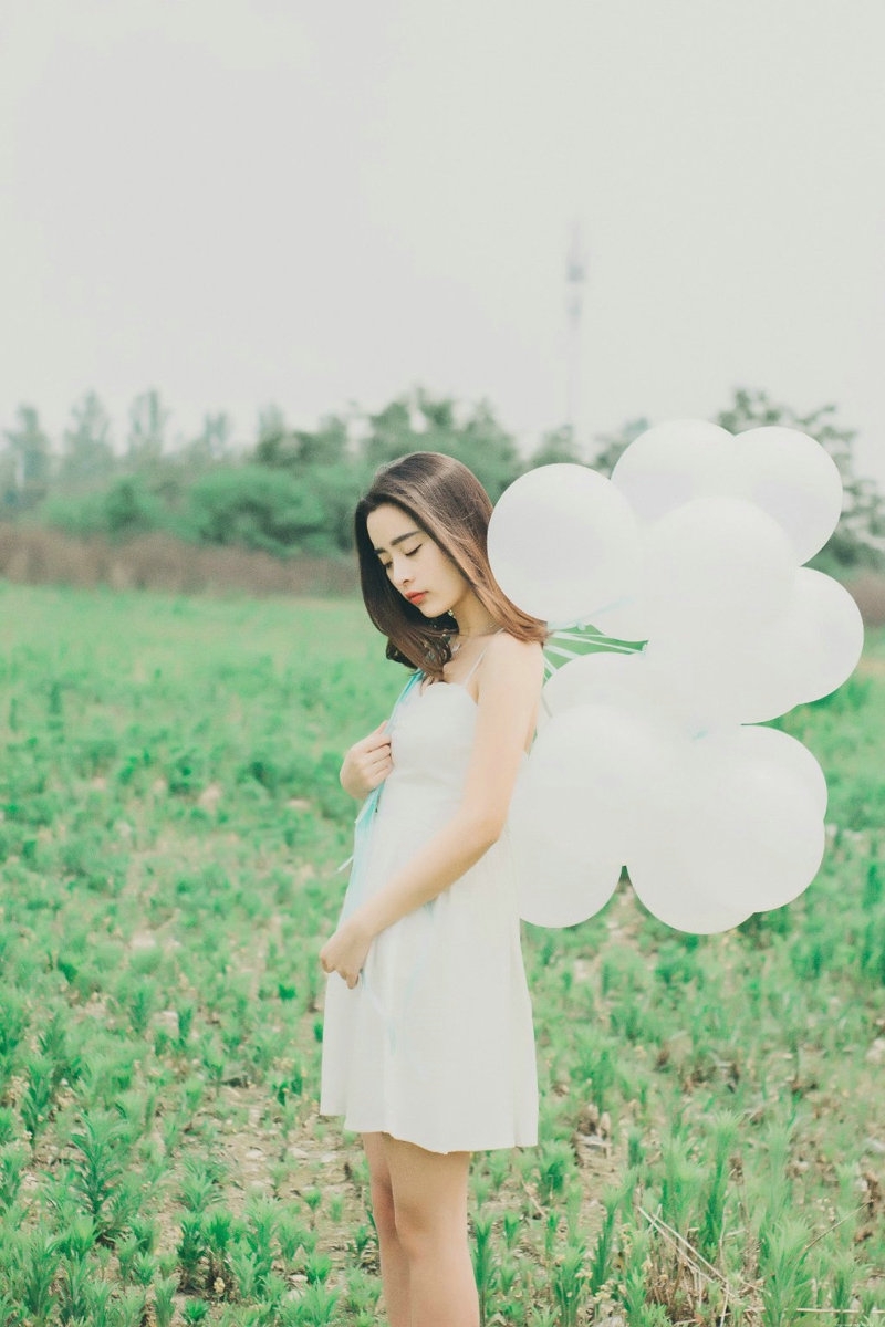 气质美女白色吊带礼裙荒野上放飞气球