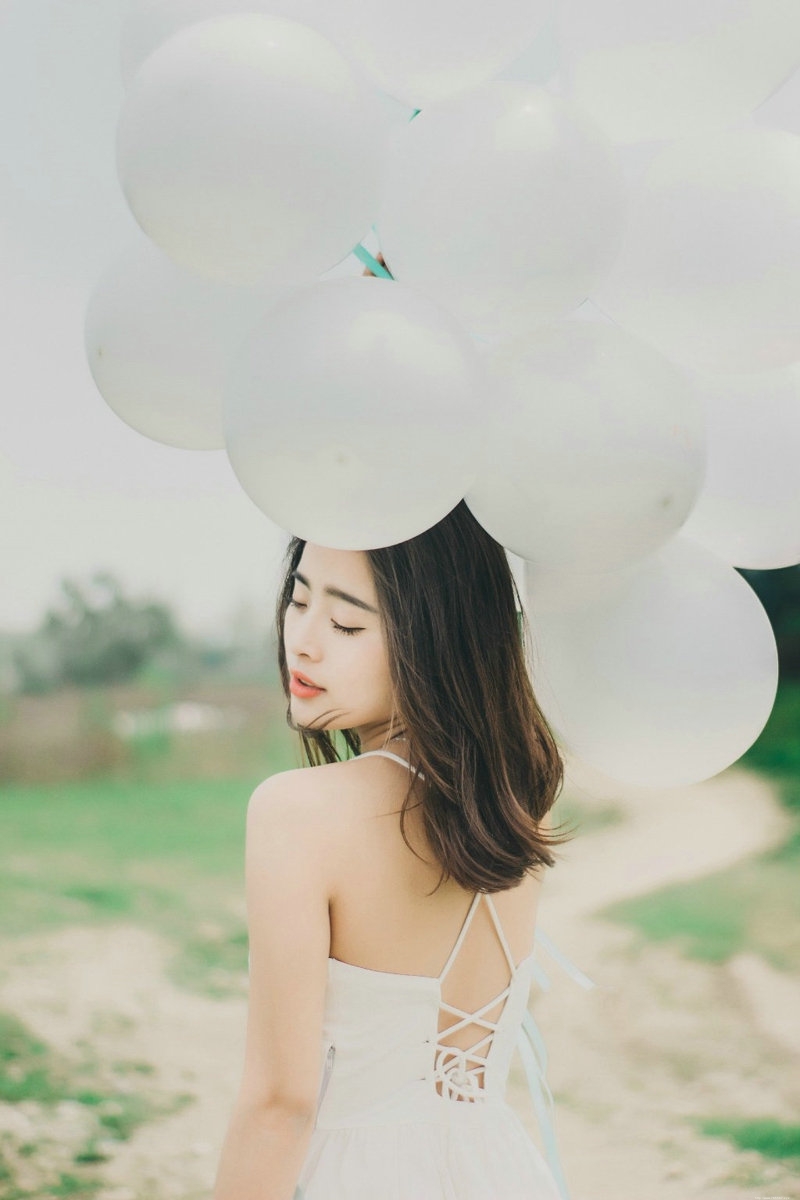 气质美女白色吊带礼裙荒野上放飞气球