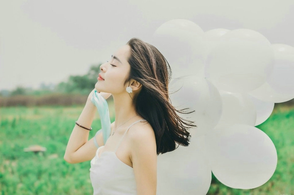 气质美女白色吊带礼裙荒野上放飞气球