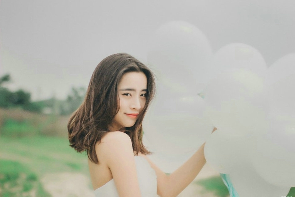 气质美女白色吊带礼裙荒野上放飞气球