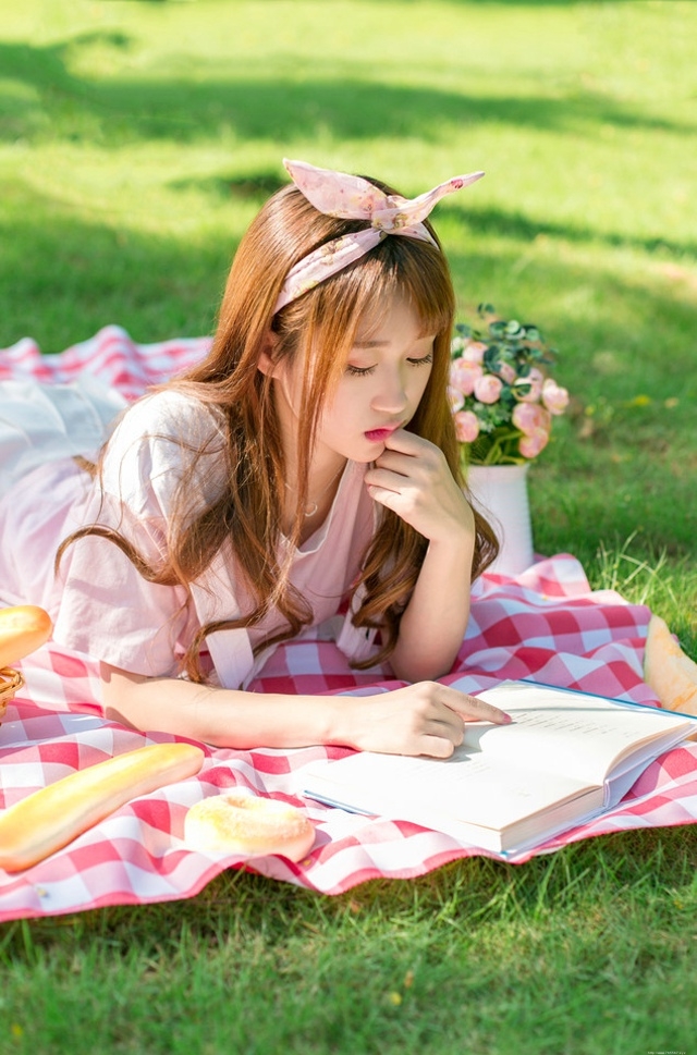 阳光下野餐少女躺在餐布上看向天空