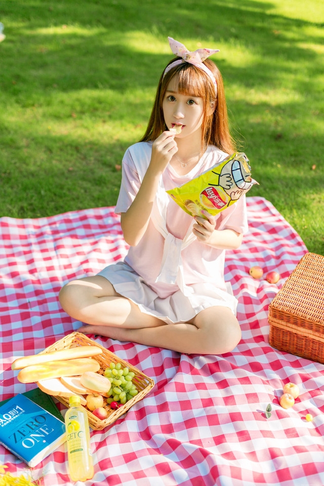 阳光下野餐少女躺在餐布上看向天空