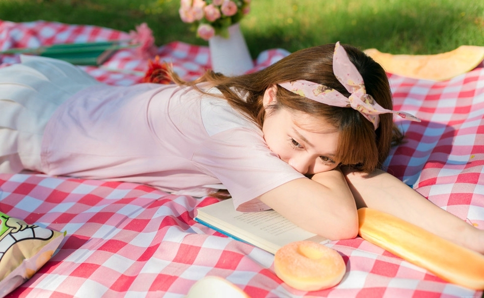 阳光下野餐少女躺在餐布上看向天空