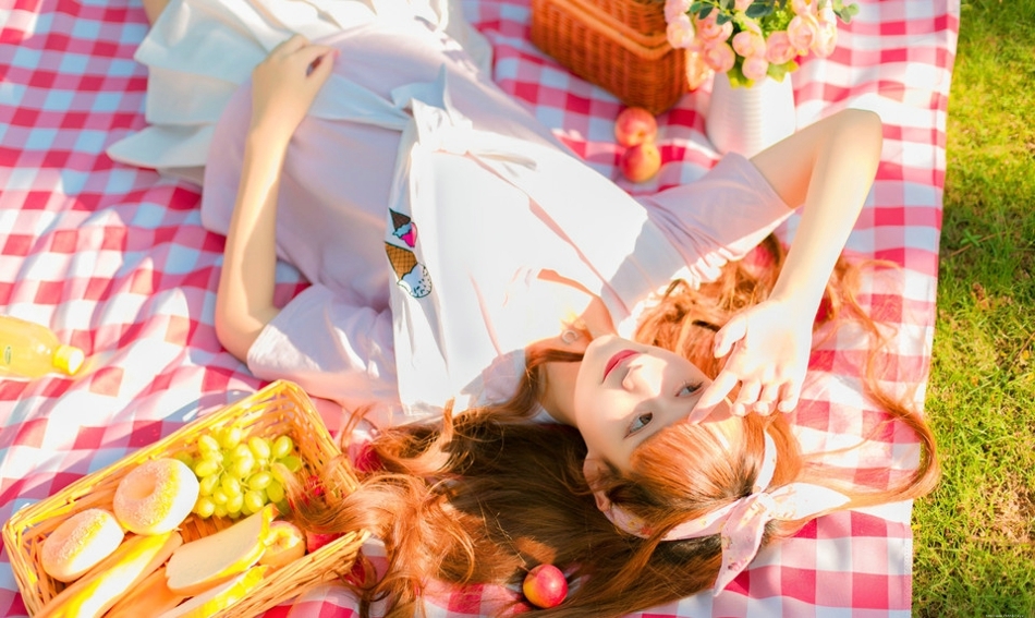 阳光下野餐少女躺在餐布上看向天空