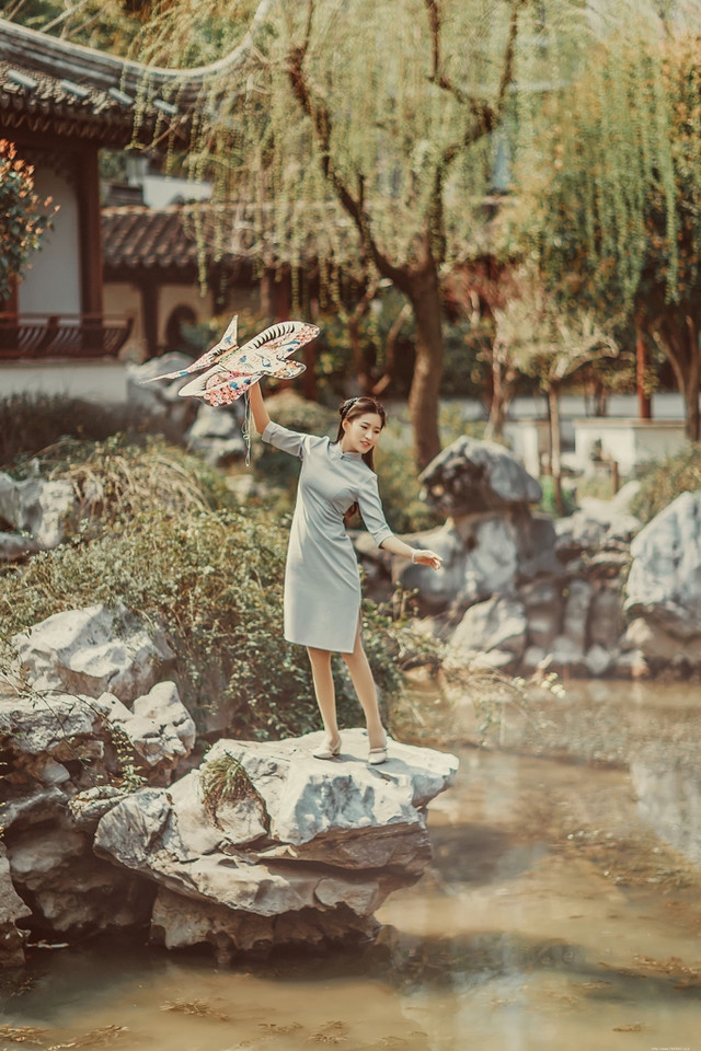 庭院内放风筝的旗袍美女展东方美池边戏水