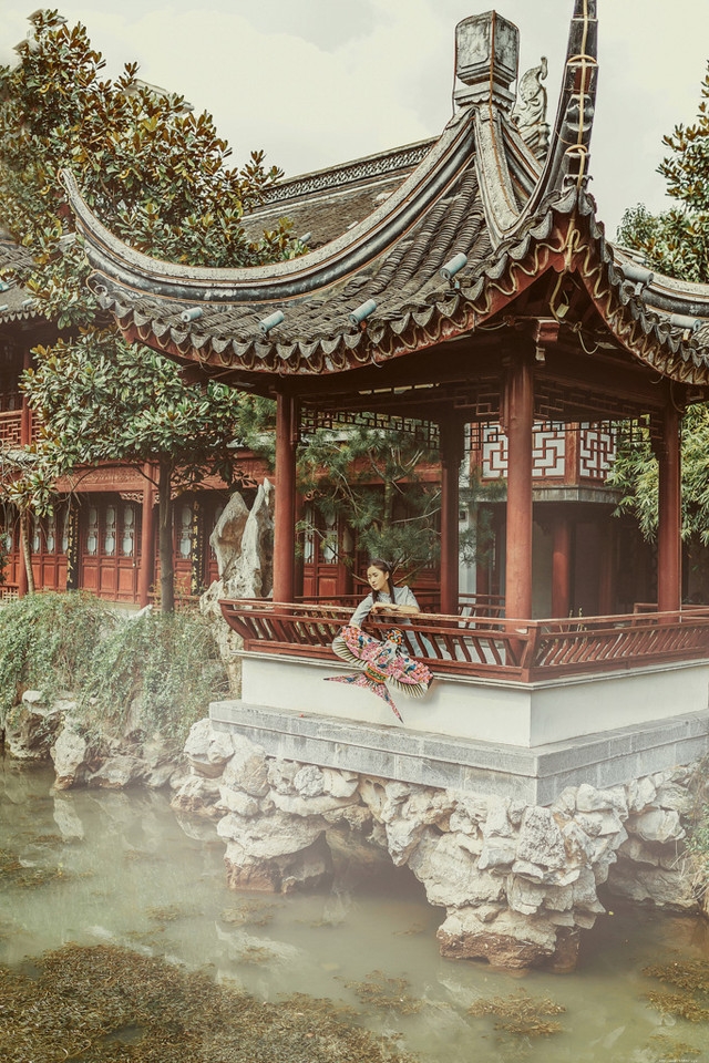 庭院内放风筝的旗袍美女展东方美池边戏水