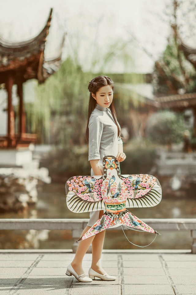 庭院内放风筝的旗袍美女展东方美池边戏水