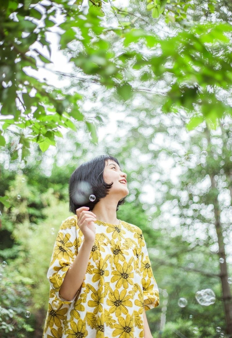 阳光下的短发向日葵妹子与泡泡玩耍