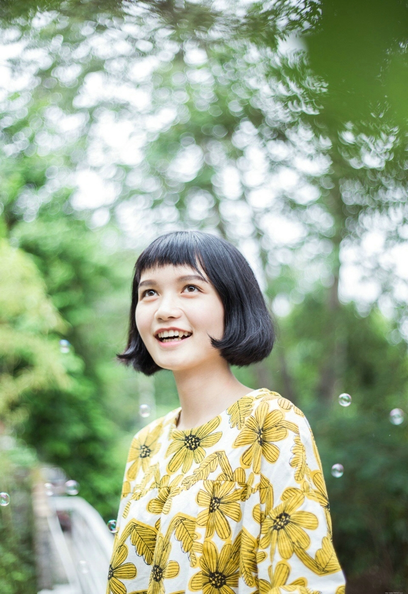 阳光下的短发向日葵妹子与泡泡玩耍