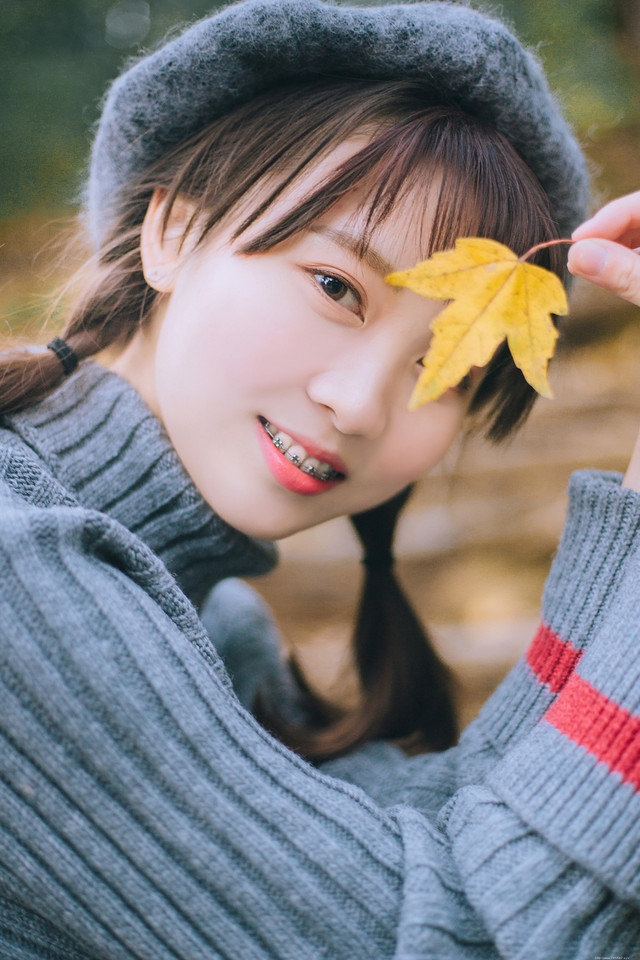 贝雷帽麻花辫美女落叶下安静看书露牙套浅笑