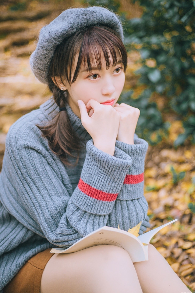 贝雷帽麻花辫美女落叶下安静看书露牙套浅笑