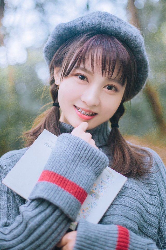 贝雷帽麻花辫美女落叶下安静看书露牙套浅笑