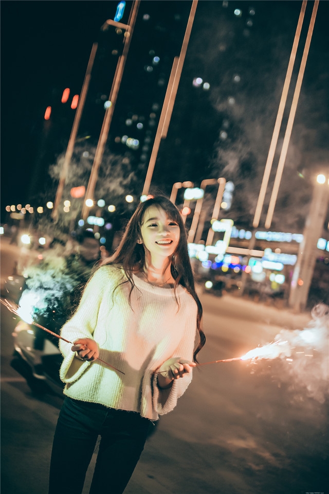 夜晚长发美女街头放烟花笑容无比愉悦