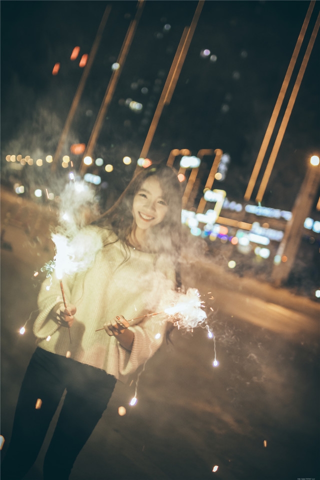 夜晚长发美女街头放烟花笑容无比愉悦