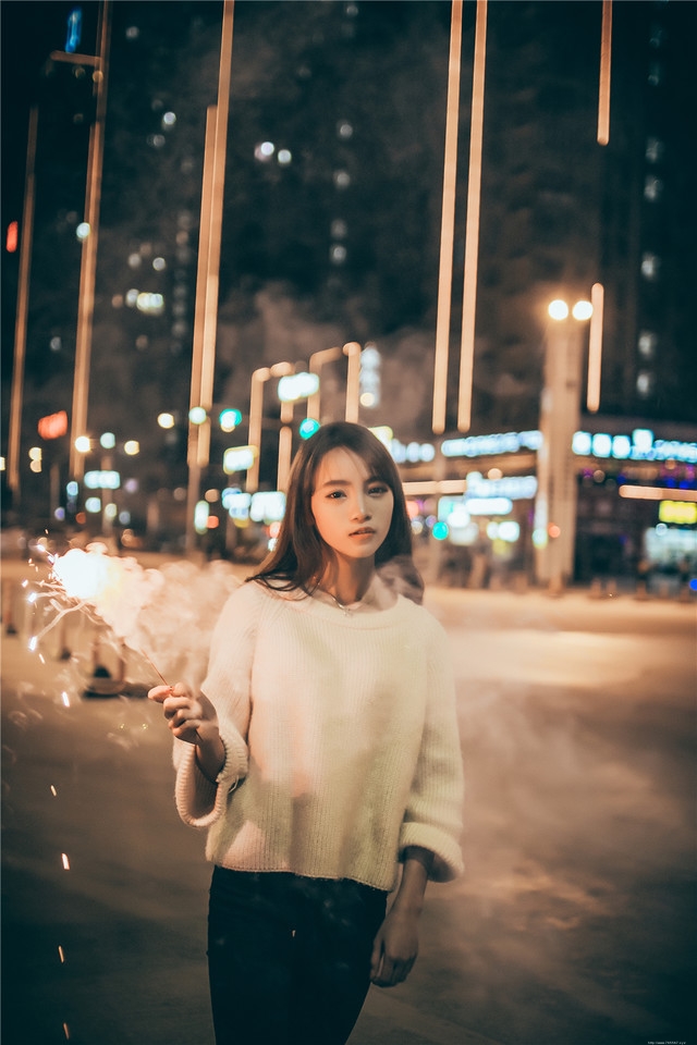 夜晚长发美女街头放烟花笑容无比愉悦