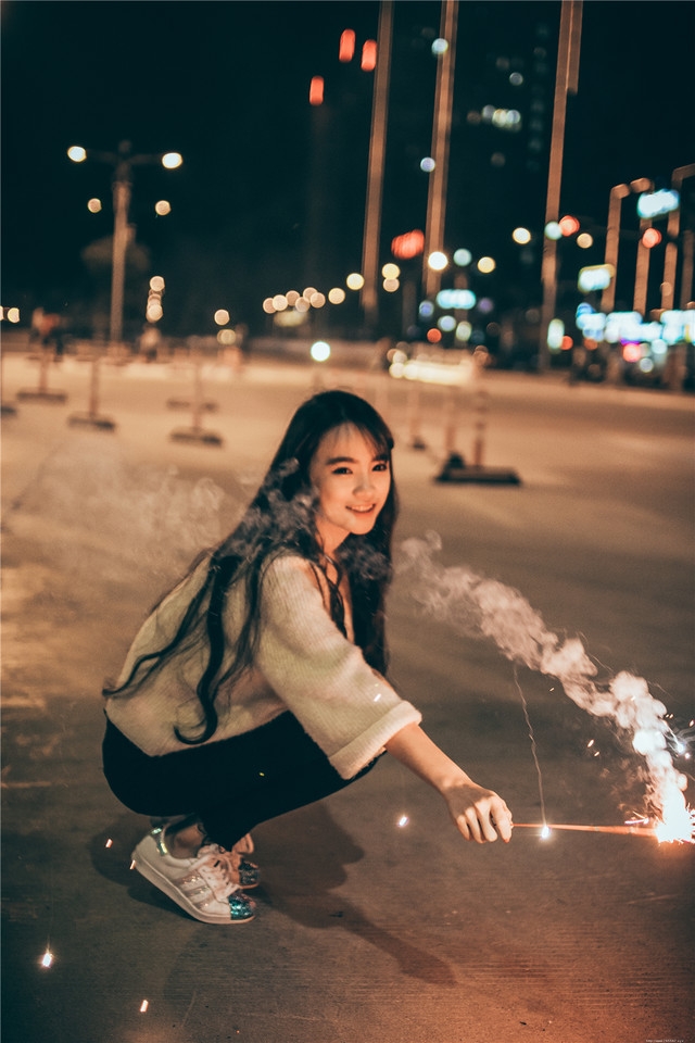 夜晚长发美女街头放烟花笑容无比愉悦