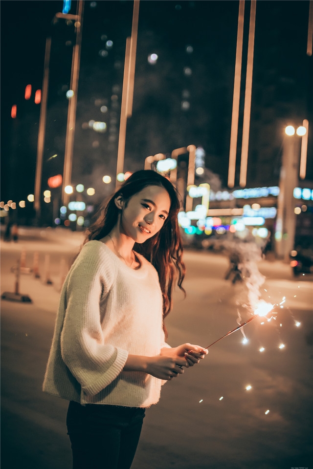 夜晚长发美女街头放烟花笑容无比愉悦