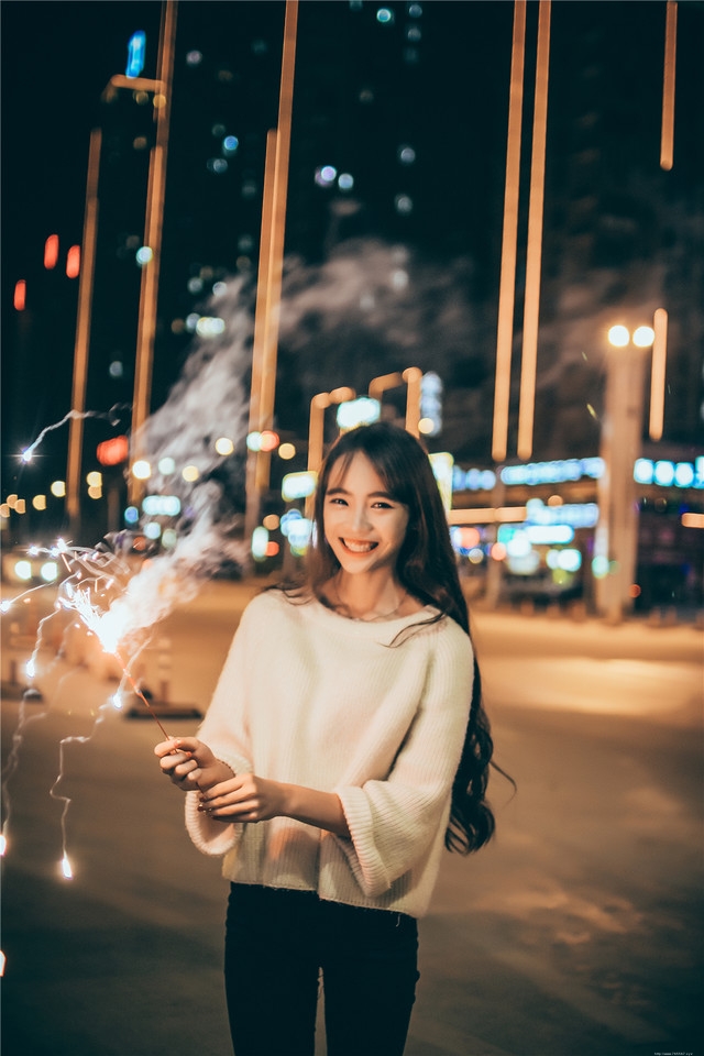 夜晚长发美女街头放烟花笑容无比愉悦