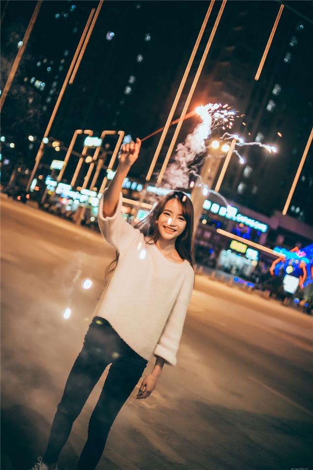 夜晚长发美女街头放烟花笑容无比愉悦
