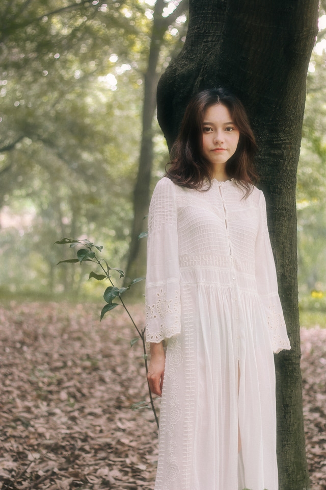 头戴花环的白色长裙美女赤脚行走在深林