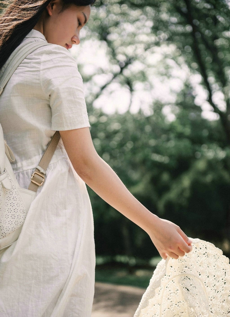 森林公园内的白裙草帽背包少女清爽怡人