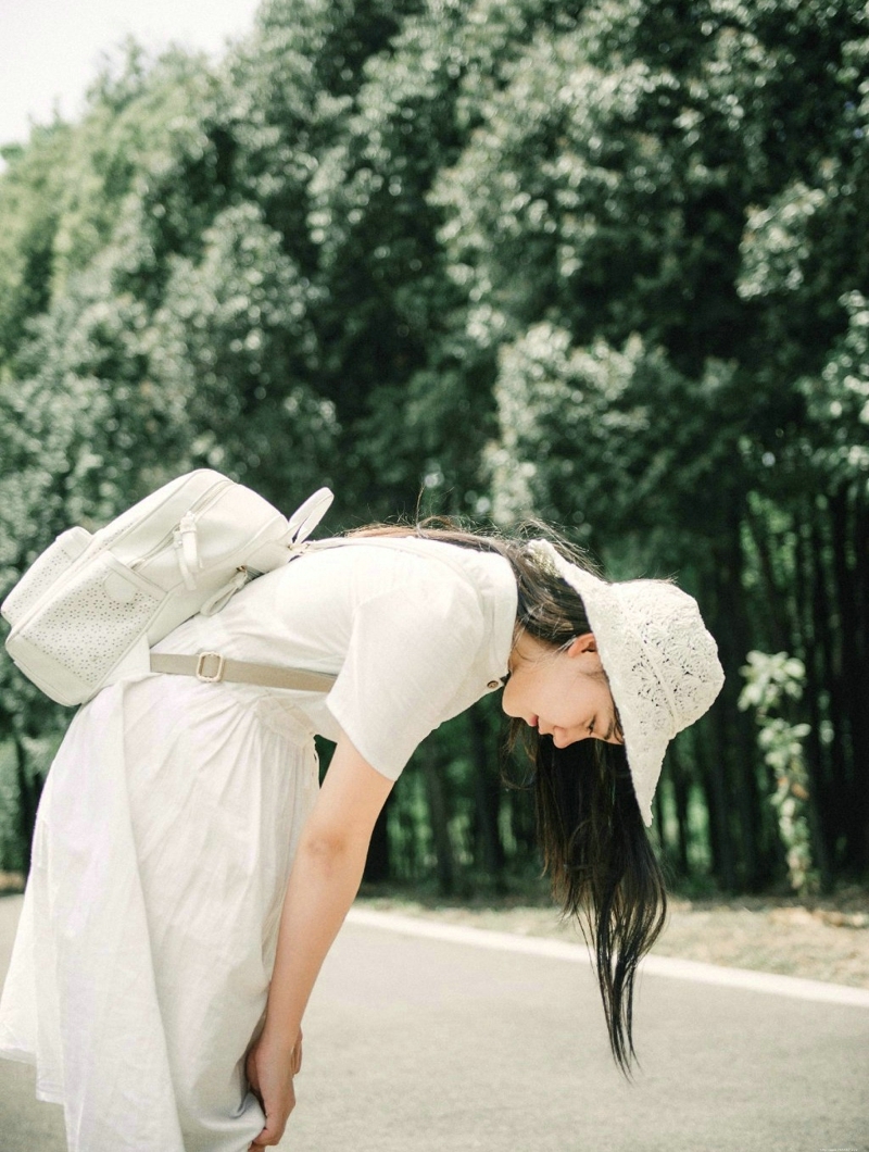 森林公园内的白裙草帽背包少女清爽怡人