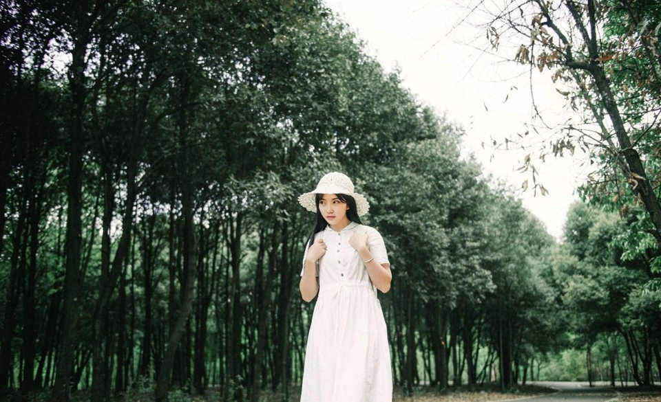 森林公园内的白裙草帽背包少女清爽怡人