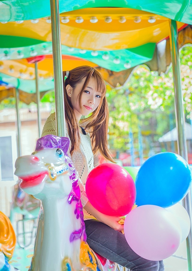 五彩缤纷的游乐场内双马尾少女坐旋转木马