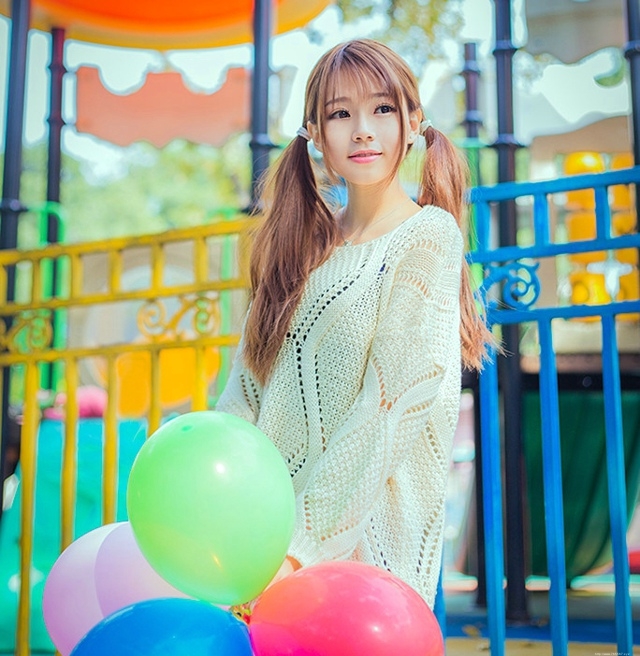 五彩缤纷的游乐场内双马尾少女坐旋转木马