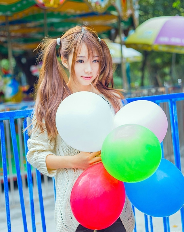 五彩缤纷的游乐场内双马尾少女坐旋转木马