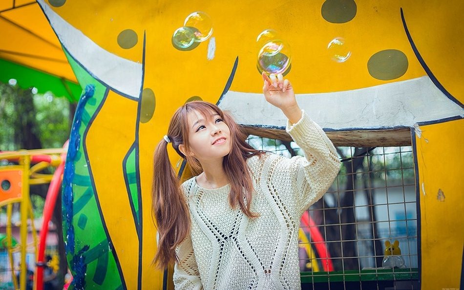 五彩缤纷的游乐场内双马尾少女坐旋转木马