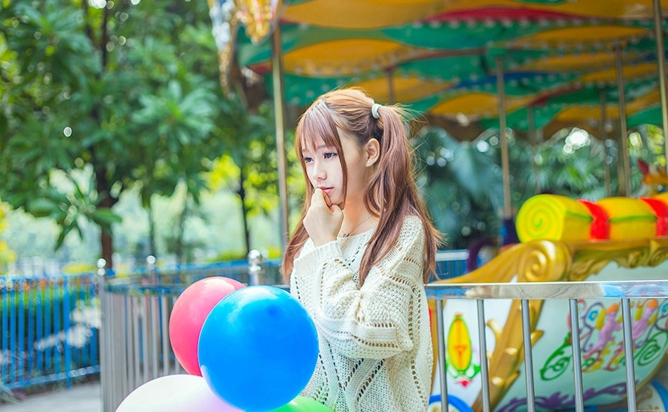 五彩缤纷的游乐场内双马尾少女坐旋转木马