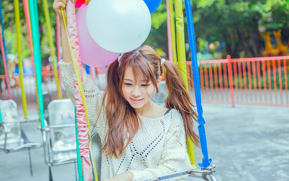 五彩缤纷的游乐场内双马尾少女坐旋转木马