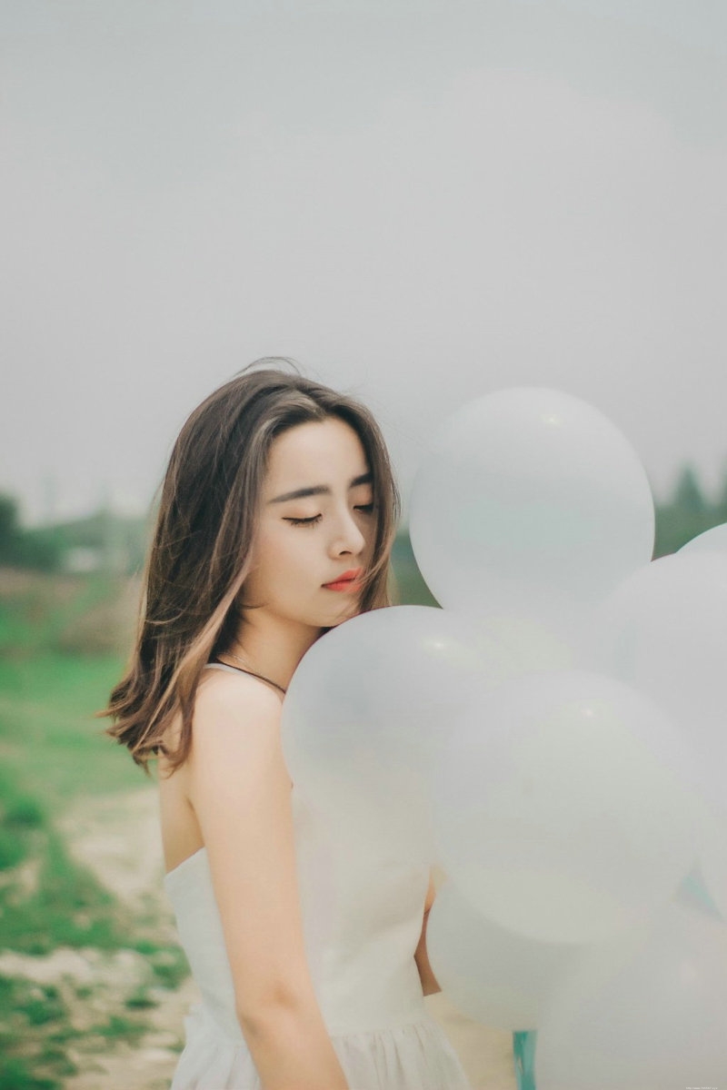 气质美女白色吊带礼裙荒野上放飞气球